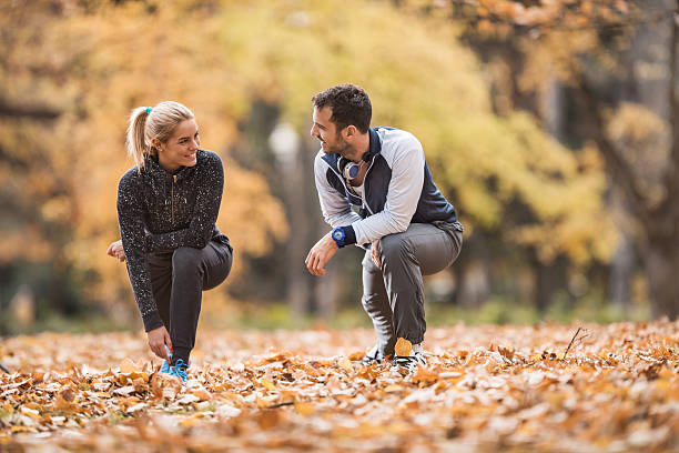 istock Smiling couple stretching their legs on autumn leaves and communicating. 504932776