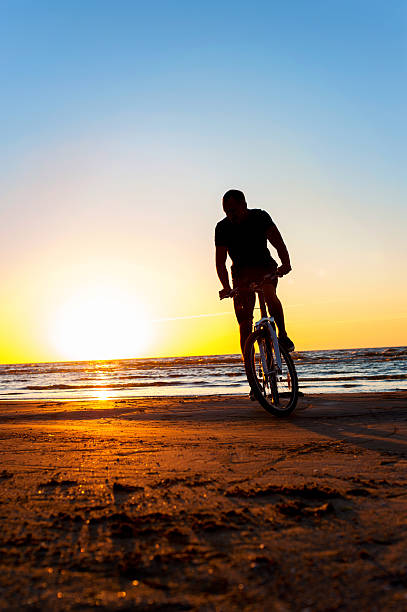 istock Man cyclist silhouette on blue sky and multicolored sunset background. 504983114