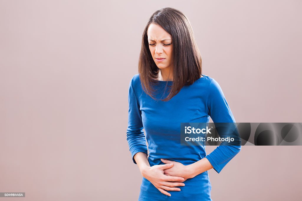 Pain in stomach Portrait of young woman who is having pain in her stomach. Adult Stock Photo