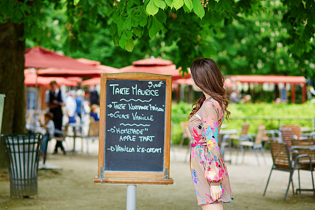 Beautiful young Parisian woman reading menu