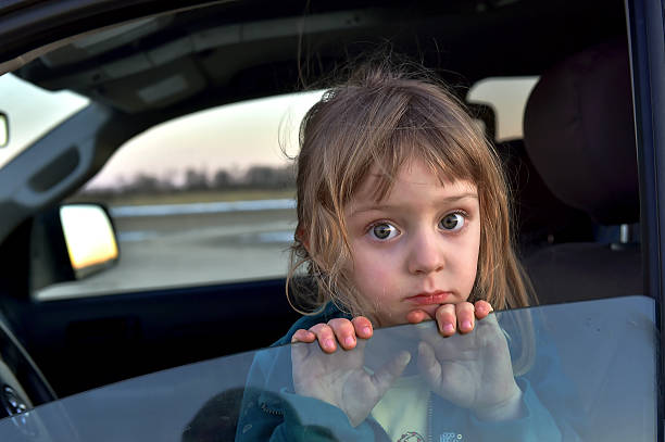 Little girl with big eyes sitting in car 