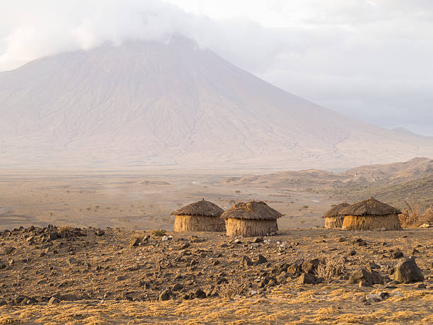 Maasai village in Arusha Maasai village in front of the Ol Doinyo Lengai (Mountain of God in the Maasai language), an active volcano in Arusha Region i the Northern Tanzania, Africa, at sunrise. arusha region stock pictures, royalty-free photos & images