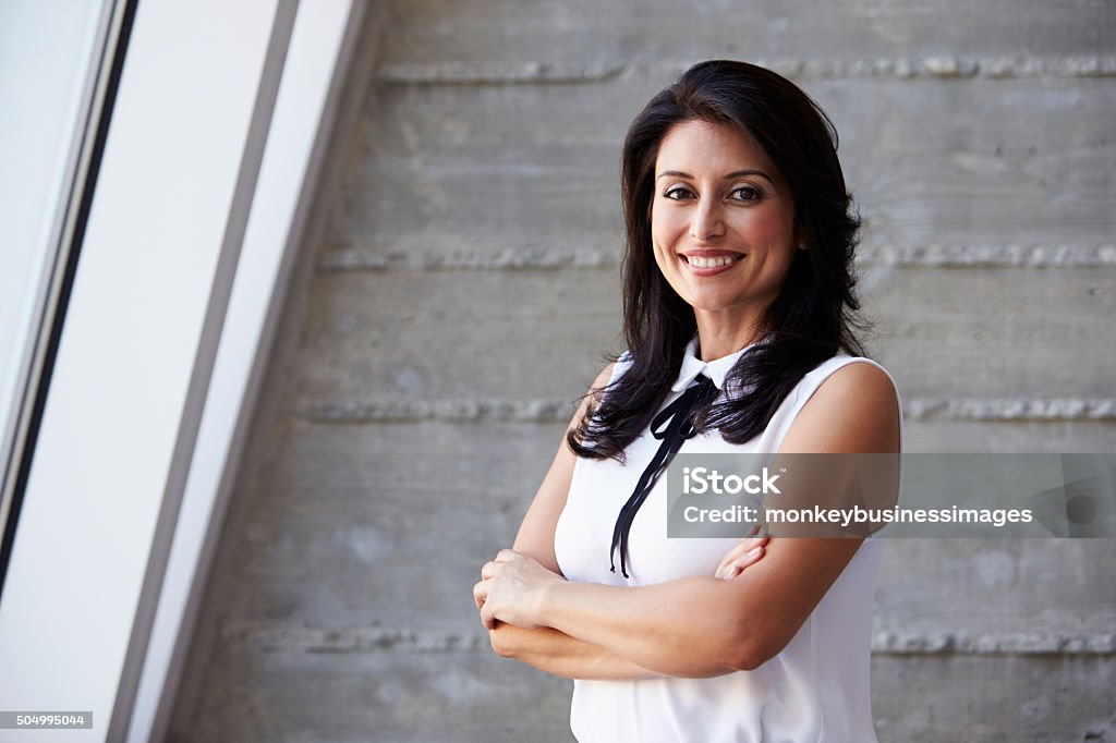 Portrait Of Businesswoman Standing Against Wall In Office Latin American and Hispanic Ethnicity Stock Photo