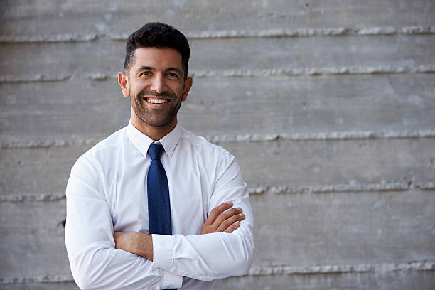 hispânico empresário de pé contra a parede em moderno escritório - shirt necktie men businessman imagens e fotografias de stock