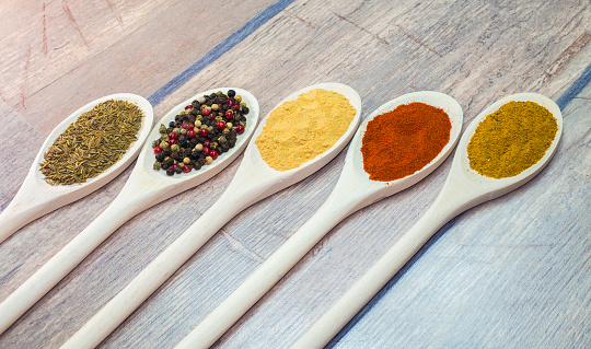 Variable colored exotic spices on wooden spoon