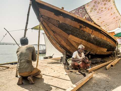 Varanasi, India - October 4, 2015: People repairing boat in Varanasi India. Varanasi is one of the oldest and holiest cities in the world. All along the riverbank of the city there are boats waiting for the pilgrims and tourists that want to navigate the river