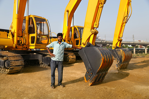 Construction worker standing near construction machinery.   