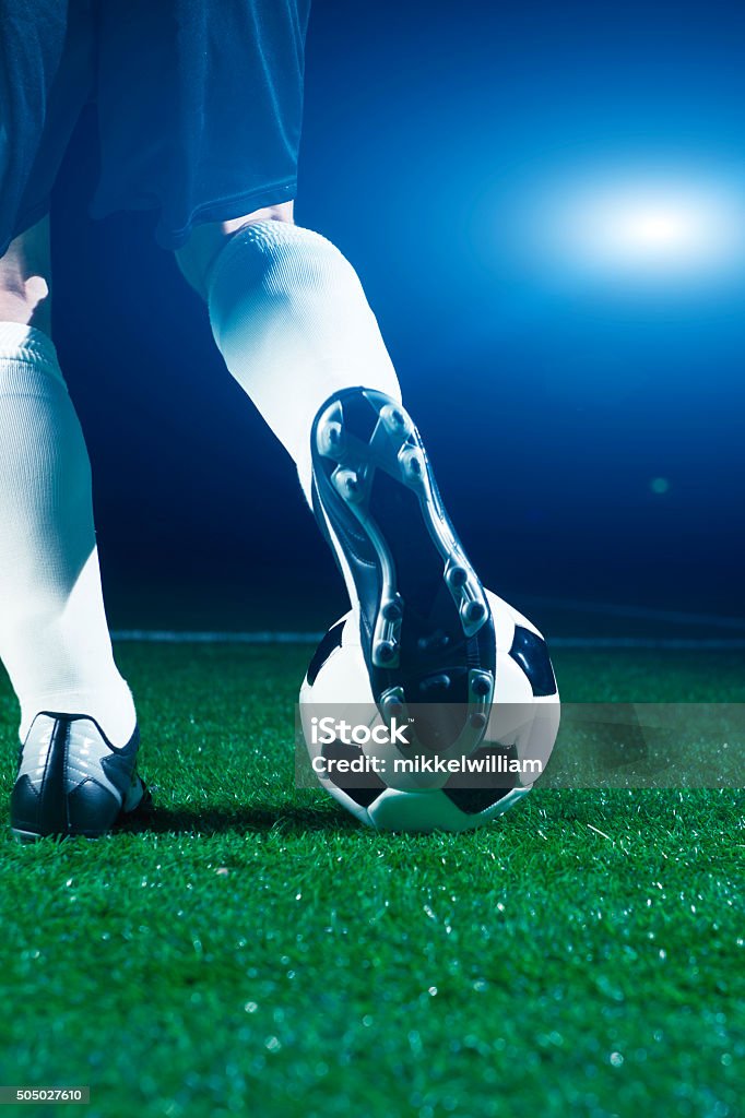 Soccer player runs to ball and kicks it Close up of soccer player who kicks a football. It is night at a soccer stadium Soccer Stock Photo