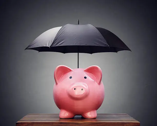 Photo of Financial insurance or protection piggy bank with umbrella