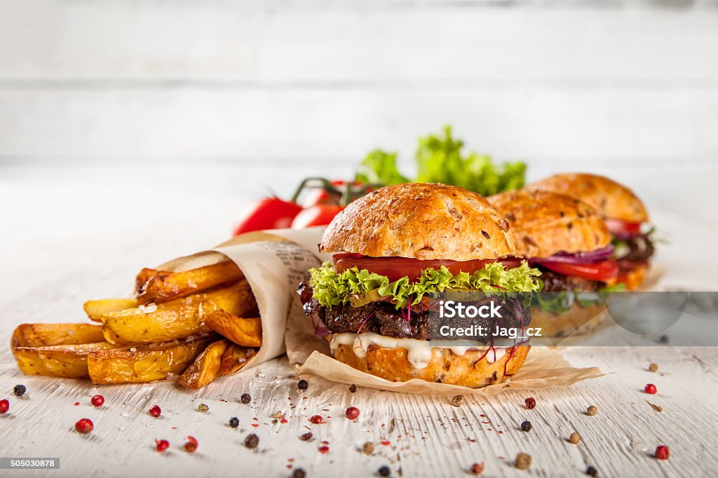 Home made hamburger with lettuce and cheese Delicious home made hamburger with lettuce and cheese, served on white old wooden desk American Culture Stock Photo