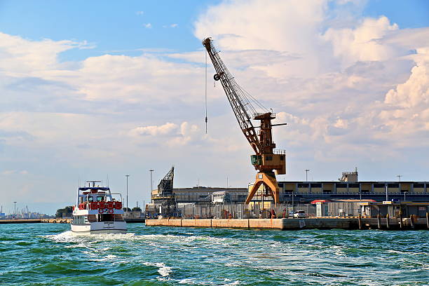 Venice, Italy - October 7th 2022:  Crane moving construction garbage into a barge at Grand Canal in the center of Venice, where everything from people and goods to garbage have to be transported in boats