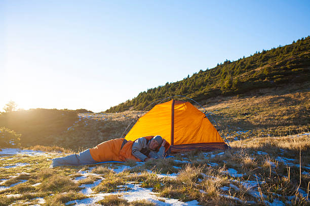 Couple lying inside a camping tent with a bicycle on the side and outside