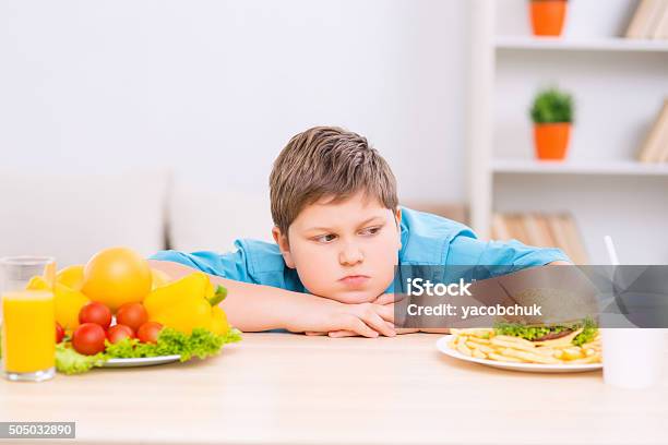 Chubby Boy Is Looking At Junk Food Plate Stock Photo - Download Image Now - Overweight, Child, Childhood