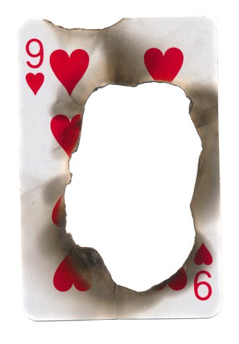 burn hole in old dirty playing card of hearts paper background. Isolated on white