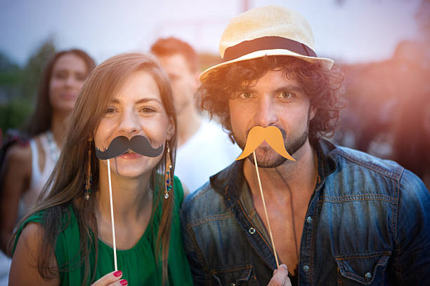 Friends having fun outdoors. Friends having fun outdoors at night club, holding masks in moustache, glasses, tie and etc. shapes. women movember mustache facial hair stock pictures, royalty-free photos & images