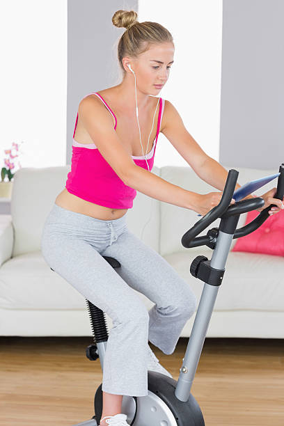 istock Sporty unsmiling blonde training on exercise bike using tablet 505051259