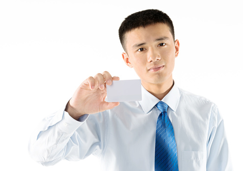 Young businessman holding a blank business card against white background.