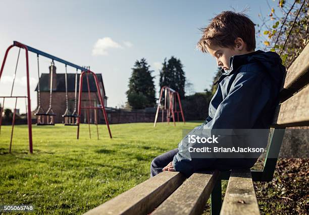 Lonely Child Sitting On Play Park Playground Bench Stock Photo - Download Image Now - Child, Sadness, Loneliness