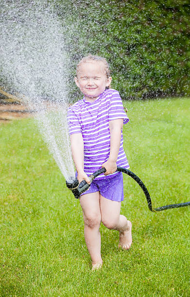 istock Girl Playing With Water Hose 505081357