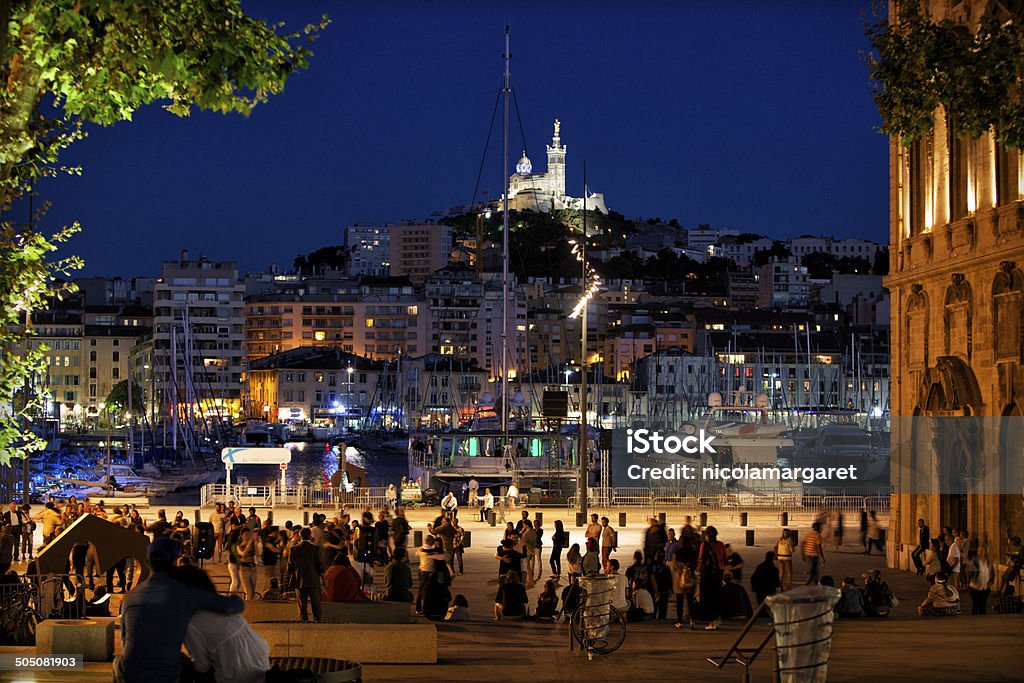 Marseille: The Old Port and Notre Dame de la Garde Night scene with motion blur of couples dancing Tango at the Vieux Port, Marseille, France. The Basilica was built on the highest point and is the most famous landmark of the city. Marseille Stock Photo