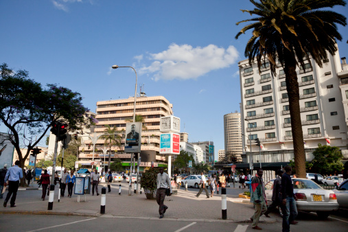 Nairobi, Kenya - February 27, 2013: Typical street scene in Nairobi. Nairobi is the capital of Kenya with an estimated population of 3 million. Cars and unidentified people in street. In background there are buildings, shops and advertising billboards. They are typical for the Nairobi city.