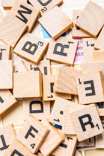 Miami, Florida, USA - May 26, 2015: Lettered wooden tiles mixed up on Scrabble game board. Scrabble is a fun and educational game distributed by Hasbro