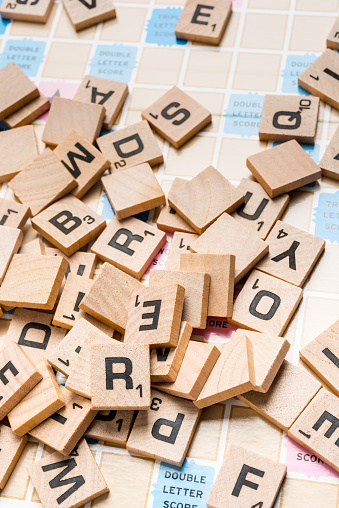 Miami,Florida, USA - May 26, 2015: Lettered wooden tiles mixed up on Scrabble game board. Scrabble is a fun and educational game distributed by Hasbro