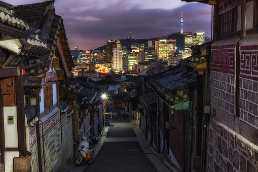 bukchon hanok village alleyway taken at sunset with the seoul n tower in the background. Bukchon hanok village is a famous tourist attraction in Seoul, South korea.