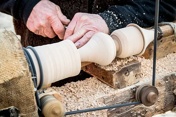 Artisan carves a piece of wood using an old manual lathe.