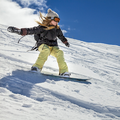Close-up shot of male legs on ski board and woman standing on skies in background while resting on ski slope