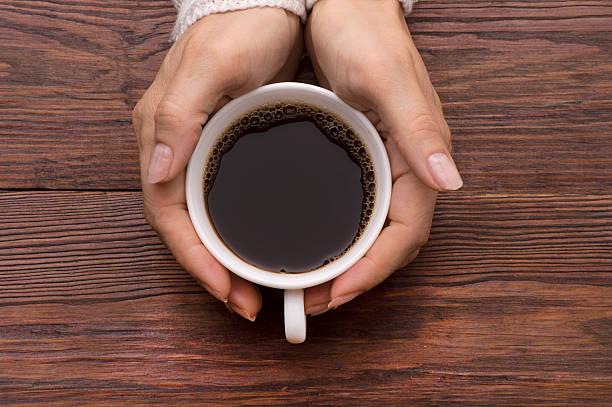 istock Female hands holding cups of coffee on rustic background 505092206