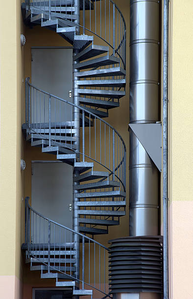 istock Spiral staircase. Fire escape / emergency exit outside industrial building 505097108