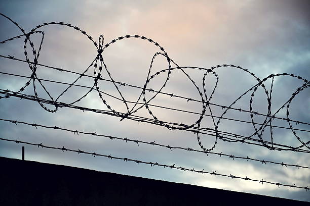 drut kolczasty ogrodzenie layed wokół więzieniu ściany - drut ostrzowy zdjęcia i obrazy z banku zdjęć