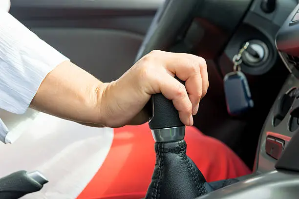 woman's hand holding a the shift lever in a car with manual transmission