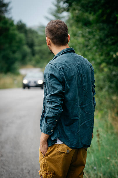 istock Young man standing on the road, looking in the car 505100126