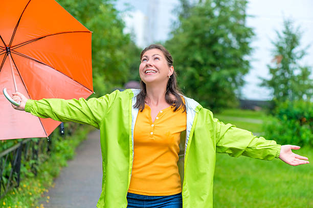 heureuse jeune femme appréciant l'été dans le parc à jets de pluie - rain women umbrella parasol photos et images de collection