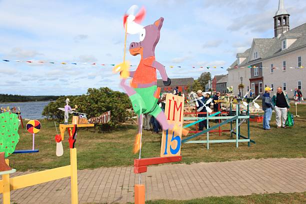 Shelburne, Canada - September 20, 2014: Whirligigs at Shelburne, Nova Scotia, Canada, whirligig festival, This festival is on annually some are for sale there. Shallow focus and motion blur due to the fact it is windy usually makes the actions of these whirligig work. Folk art.  People in the picture are looking at whirligigs and some will be buying them. Some people with cameras are taking pictures of them.