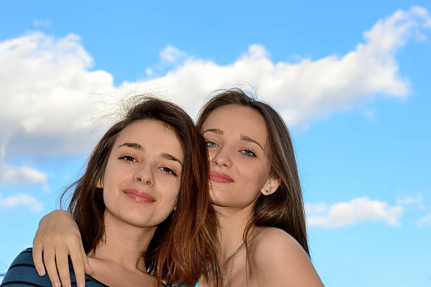 istock Two beautiful young women standing over blue sky and hugging 505116615