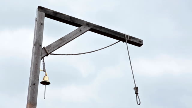 Wooden gallows with swinging noose rope and golden bell