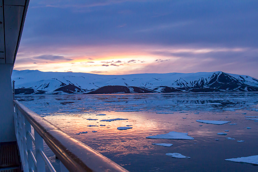 Arctic glow of summer sunset reflecting in Whaler Bay, Deception Island, Antarctica with deck of cruise ship.