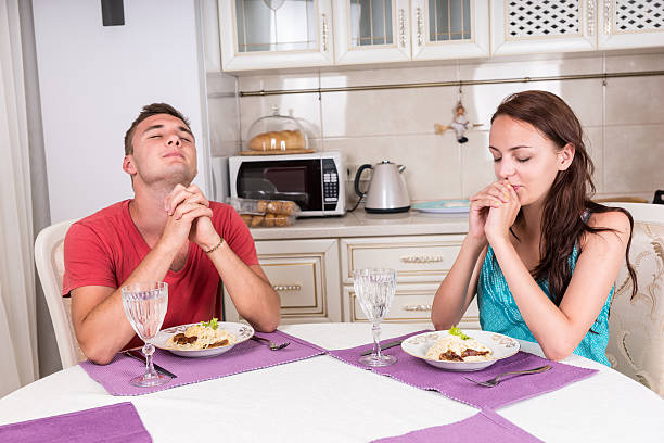 casal jovem dizendo graça antes de comer a refeição - praying meal saying grace in front of imagens e fotografias de stock