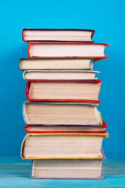 istock Stack of colorful hardback books, open book on blue background 505132114