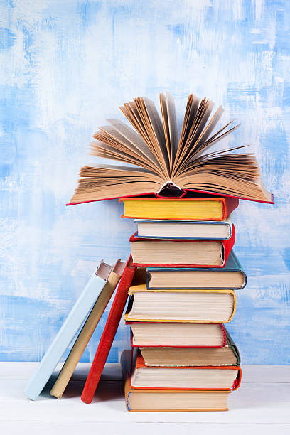 istock Stack of colorful hardback books, open book on blue background 505132576