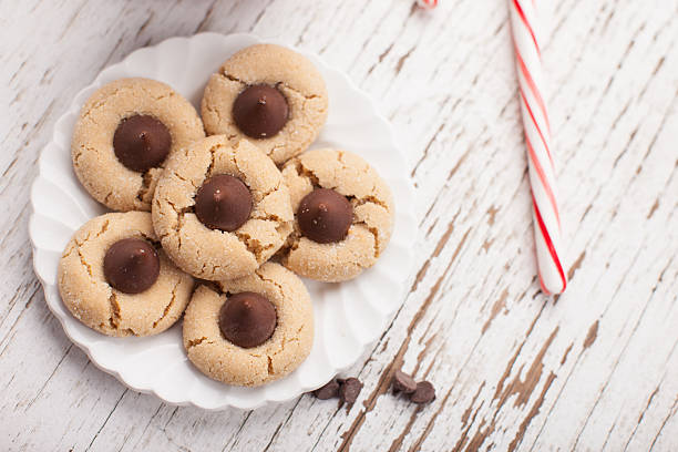Top view of peppermint candy cane and chocolate peanut blossom cookies on weathered white wood