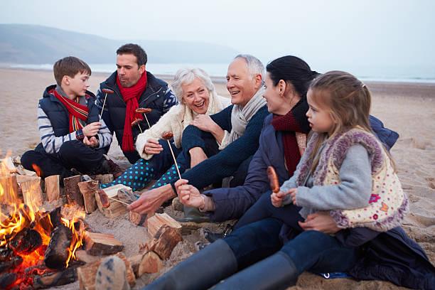 Multi Generation Family Having Barbeque On Winter Beach Multi Generation Family Having Barbeque On Winter Beach Smiling family bbq beach stock pictures, royalty-free photos & images