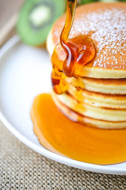 istock pouring syrup on stack of pancake on white plate 505159282
