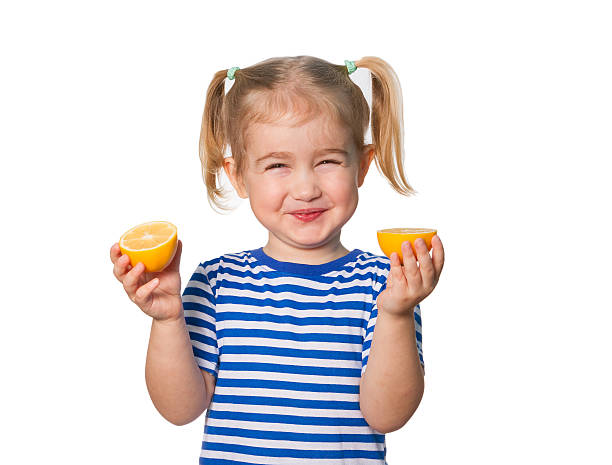 Little Funny girl keeps lemons Little Funny girl in striped shirt  keeps lemons. Isolated on white background sour face stock pictures, royalty-free photos & images