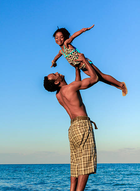 istock Father holding daughter in air at beach 505165022