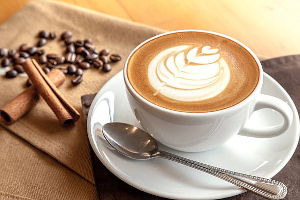 tasse café latte macchiato mit kaffeebohnen und zimt - schaumiges getränk fotos stock-fotos und bilder