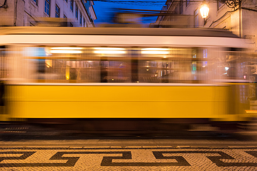 Motion blurred image of a classic yellow tram in Lisbon, Portugal at dusk
